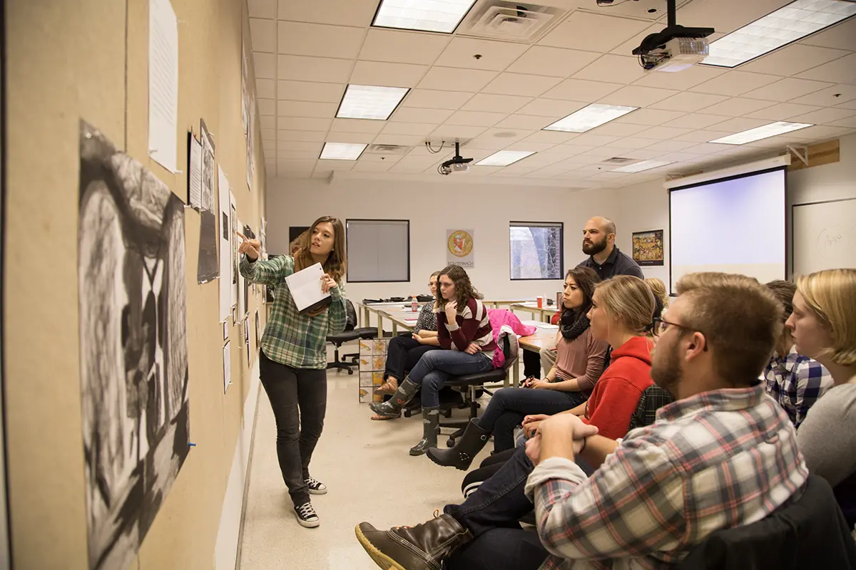 A student presents artwork in front of a class