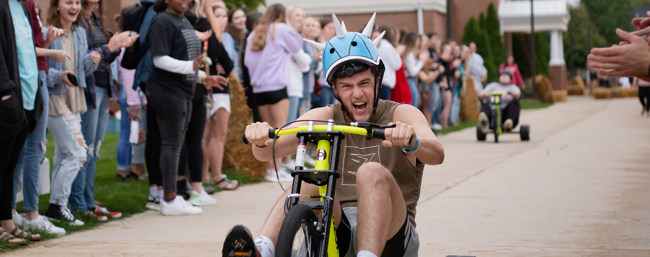 Student riding tricycle at IWU homecoming