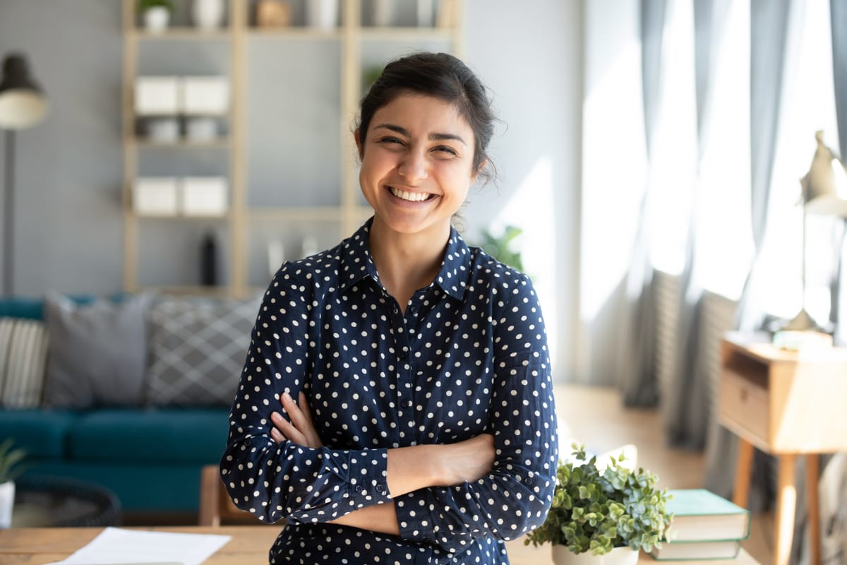 Smiling young woman standing and looking at camera with arms crossed.