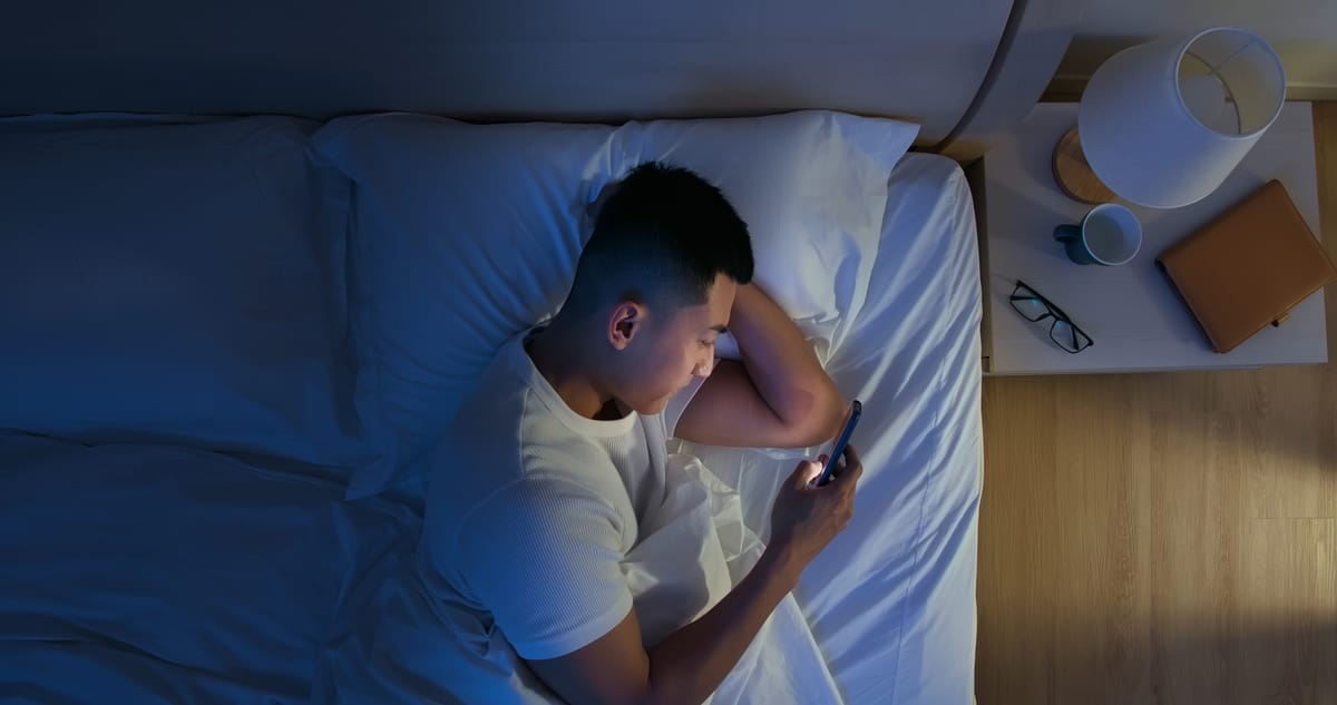 Overhead view of man using smartphone at night in bed