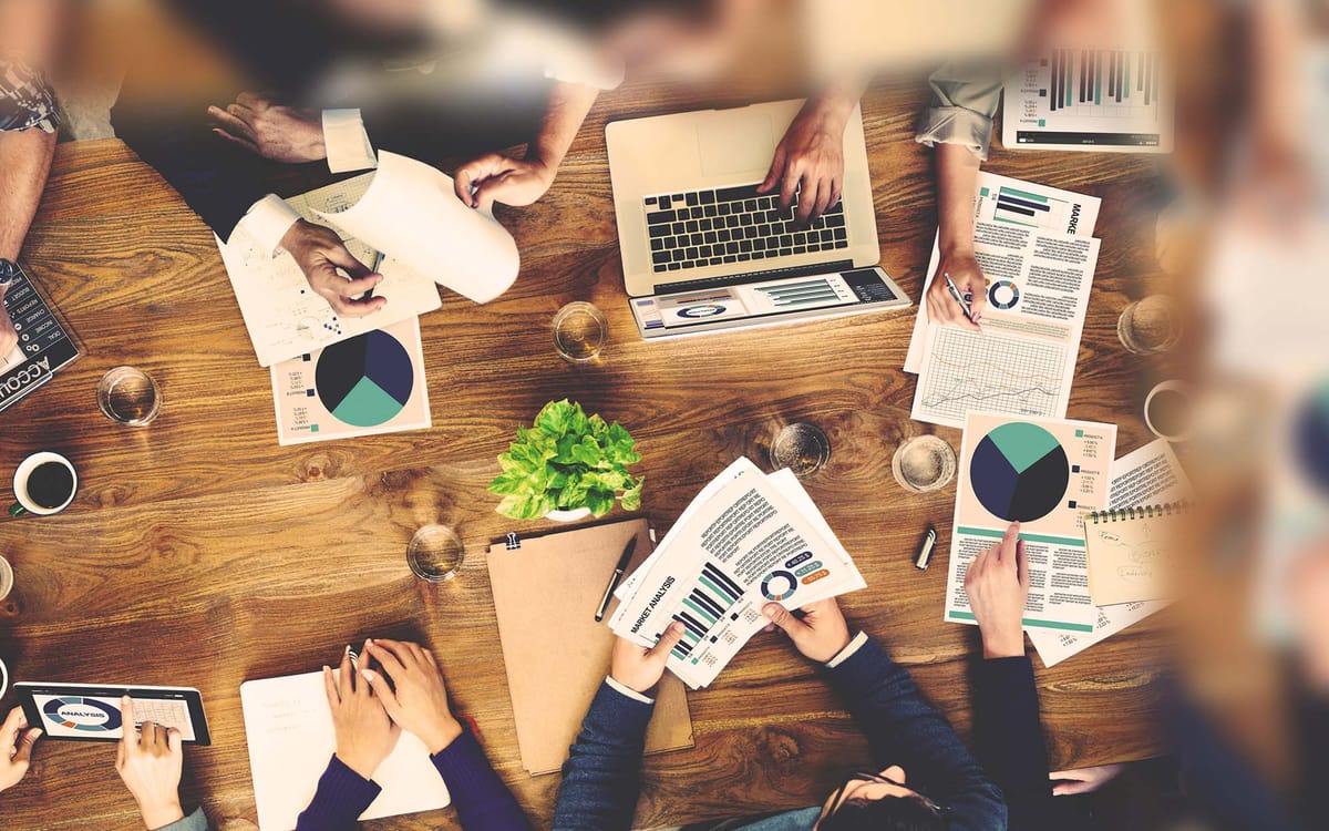 Overhead shot of a group of professionals seated around a wooden table engaged in a collaborative business meeting.