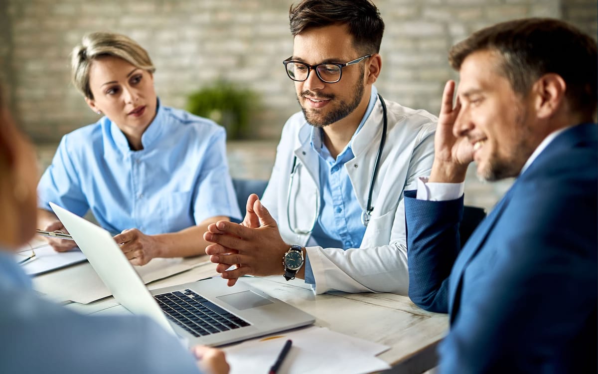 A group of healthcare professionals and a businessperson having a collaborative meeting.
