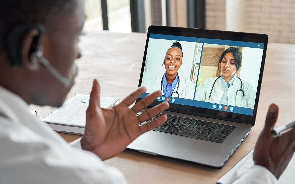 Doctor speaking with two other doctors via video call on a laptop