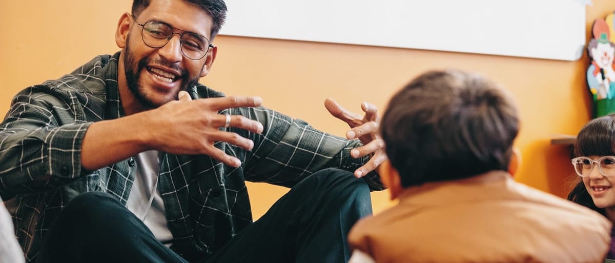 Teacher sitting on the floor surrounded by young students