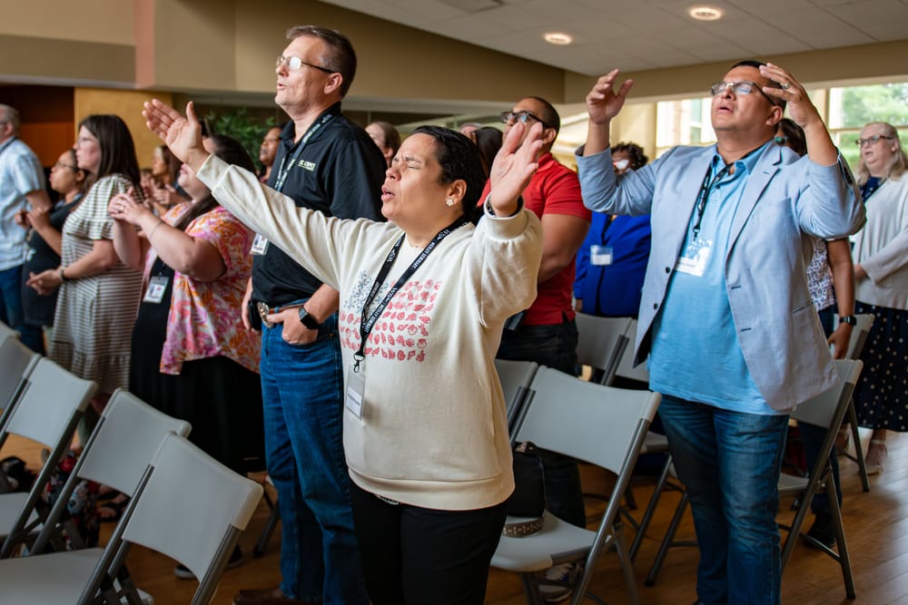 People standing in rows with hands raised in worship.