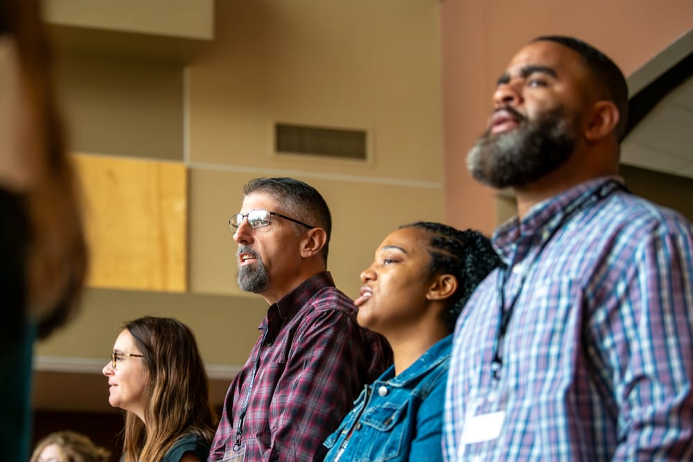 Group of people singing together during a gathering.