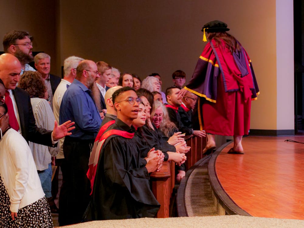 People placing hands on graduates in prayer.