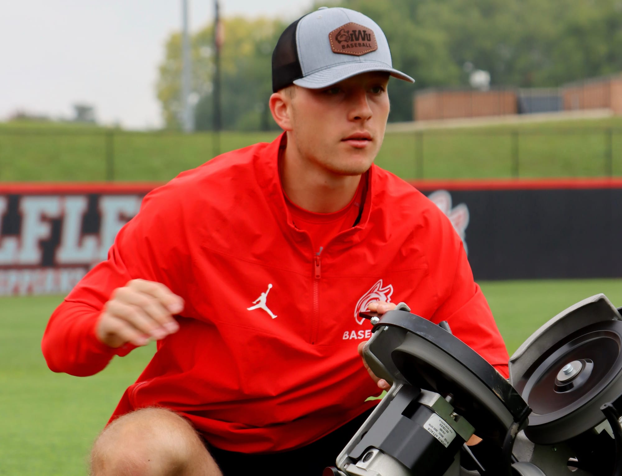 Chase Gerbrick on baseball diamond by baseball pitching machine 