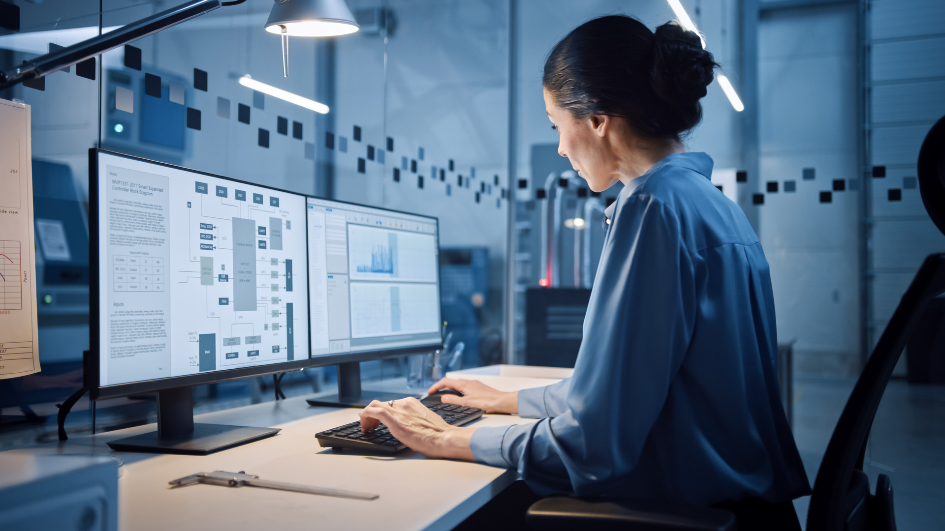 Woman working across 2 computer screens