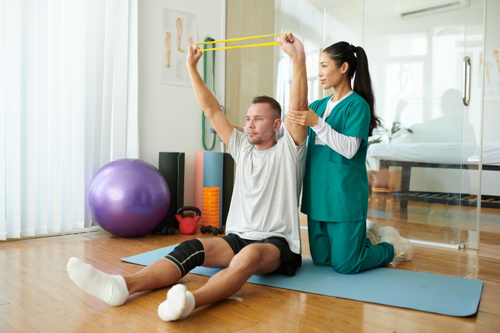 Therapist controlling patient keeping arms straight when exercising with resistance band