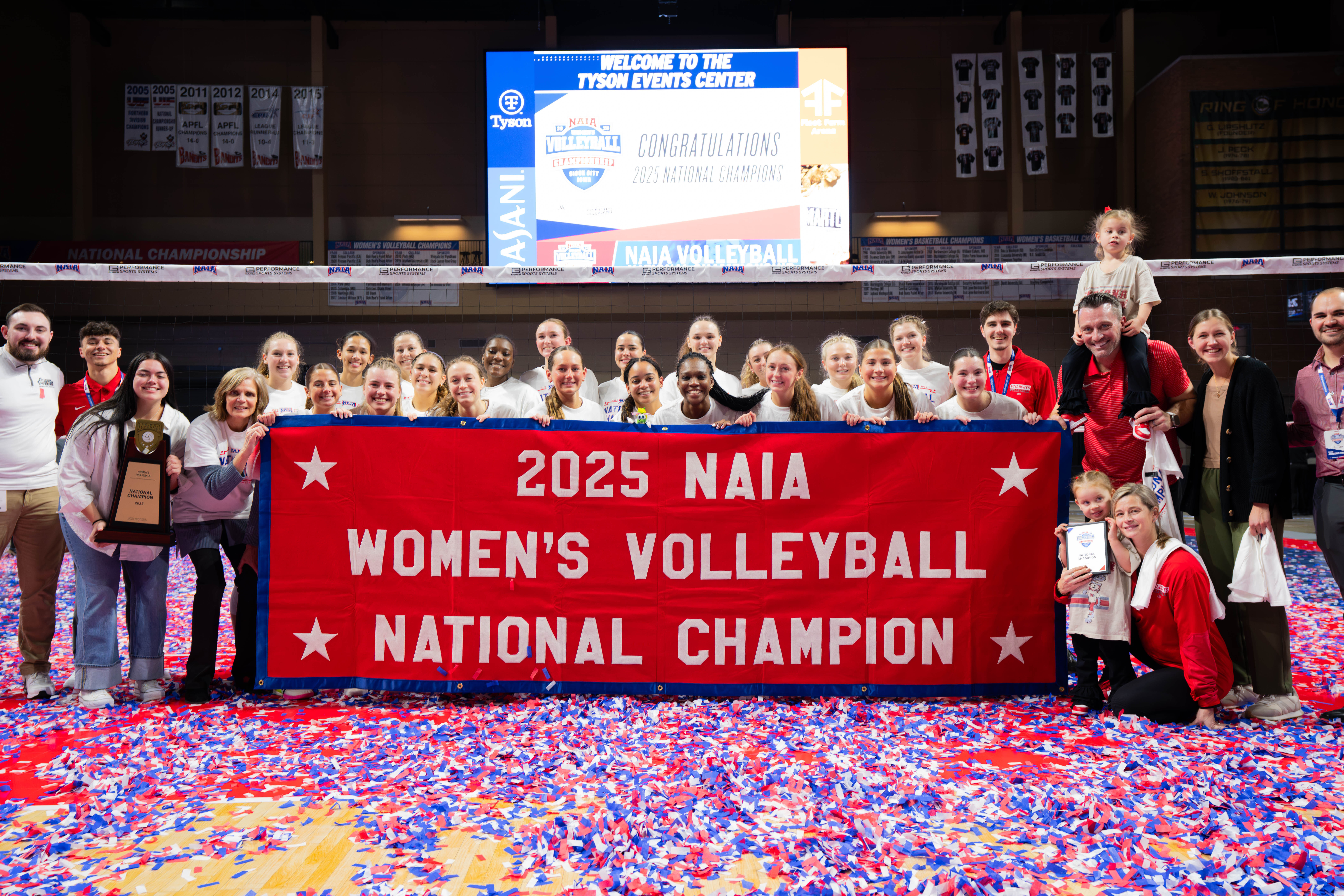 IWU volleyball team holding &quot;2025 NAIA Volleyball National Champion&quot; banner