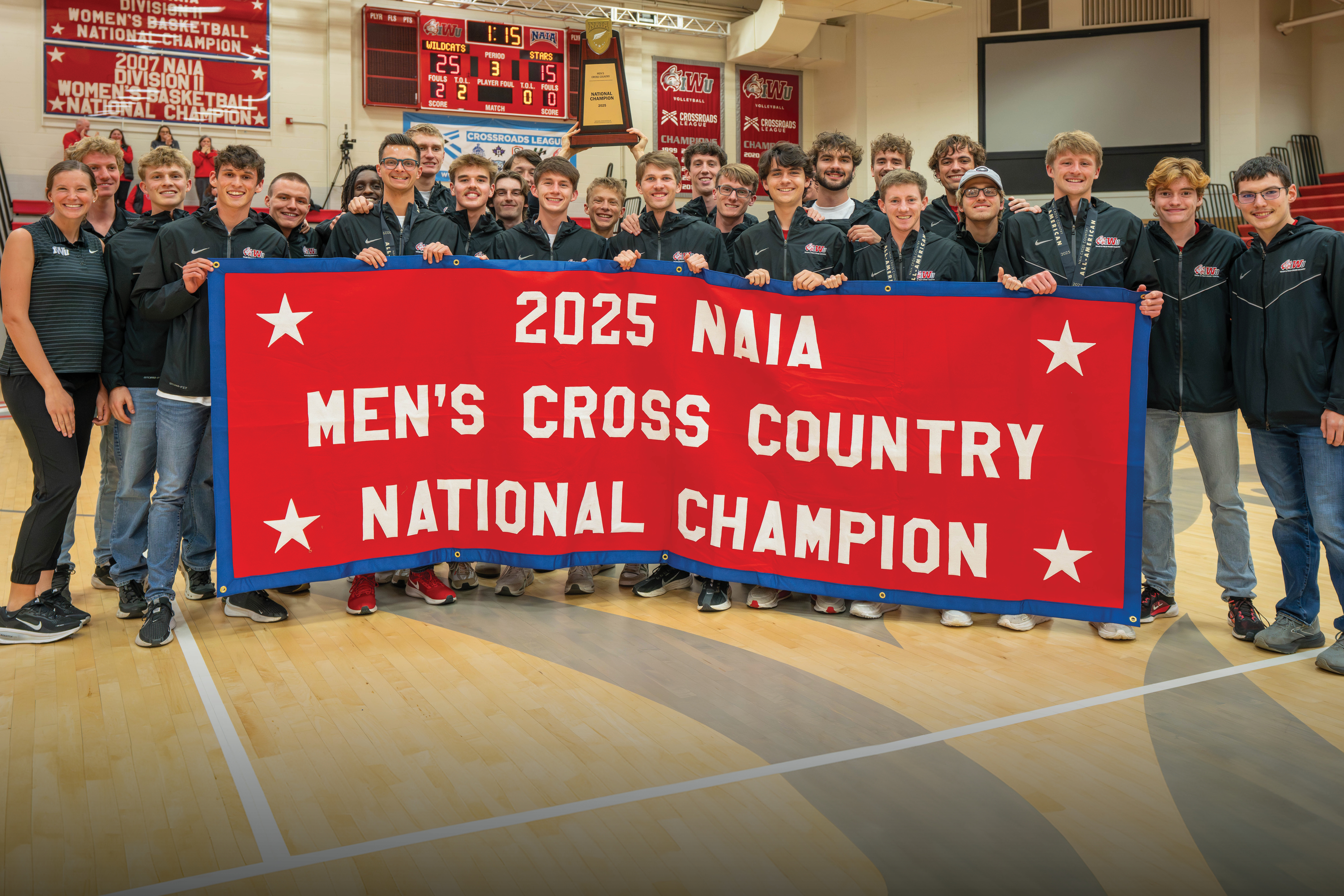 IWU Men's Cross Country team holding large red banner which says, "2025 NAIA Men's Cross Country National Champion"