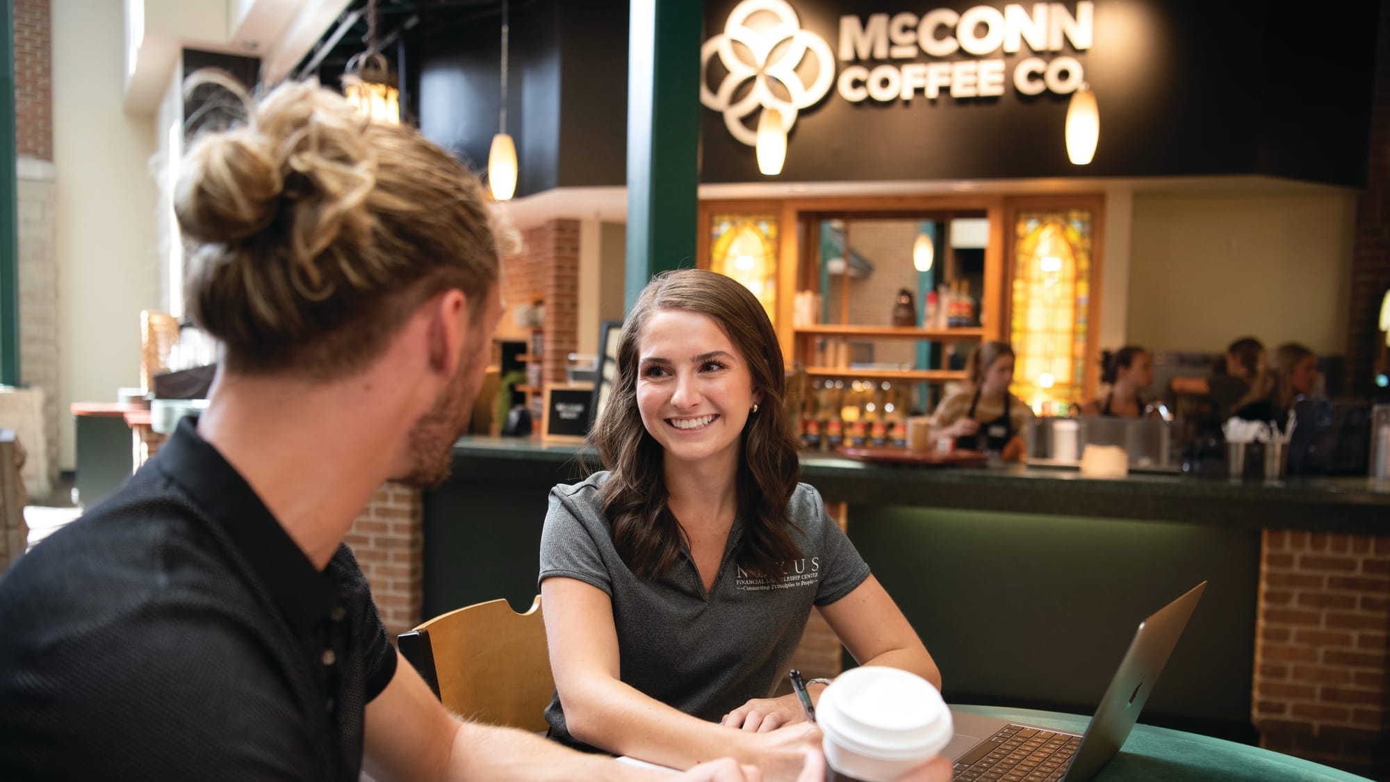Two people sitting at table near McConn coffee