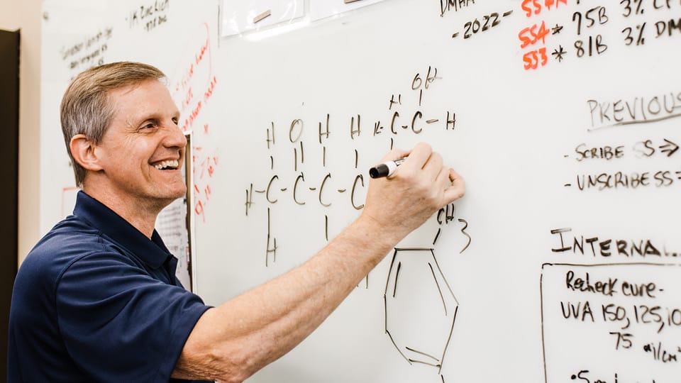 Rob Raymond writing chemical equation on white board