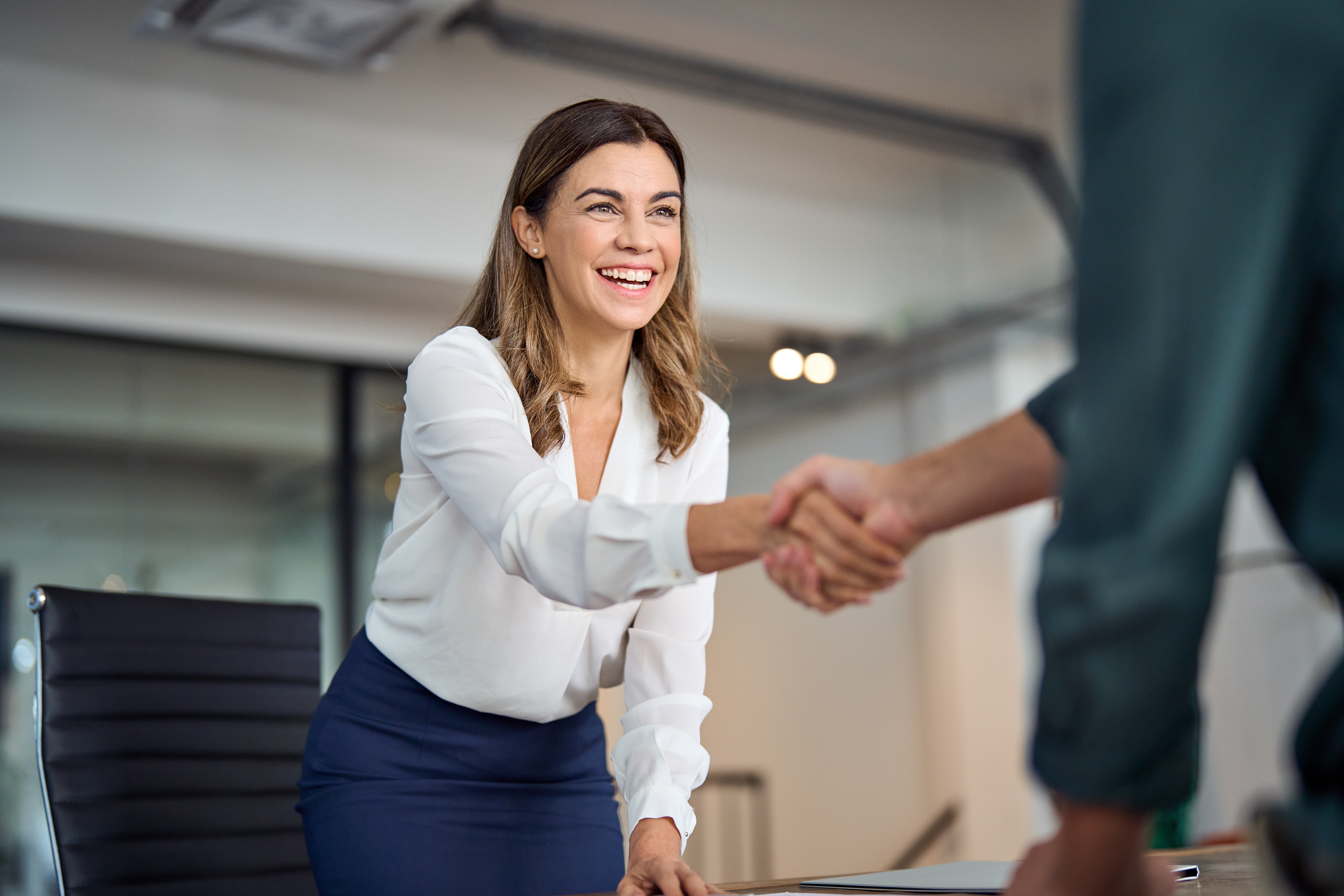 mid aged business woman manager handshaking greeting client in office.
