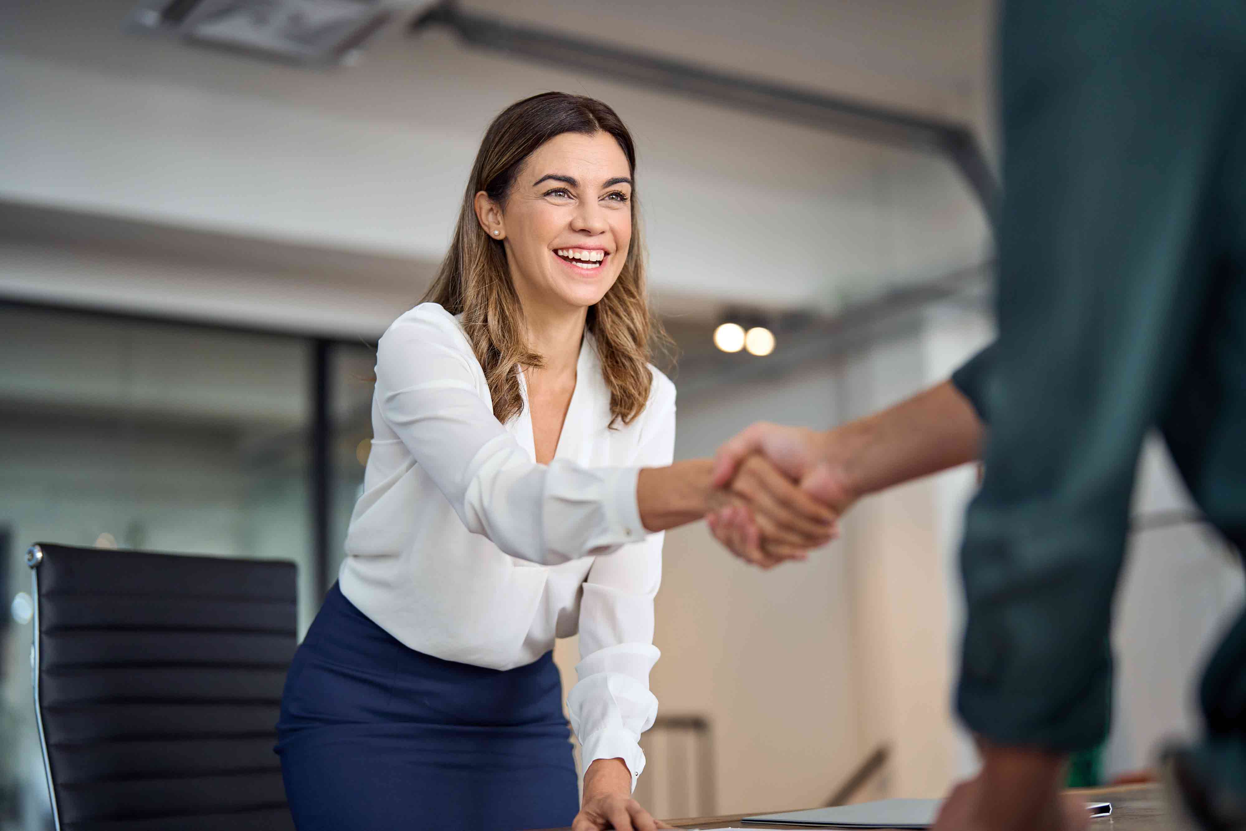 mid aged business woman manager handshaking greeting client in office.