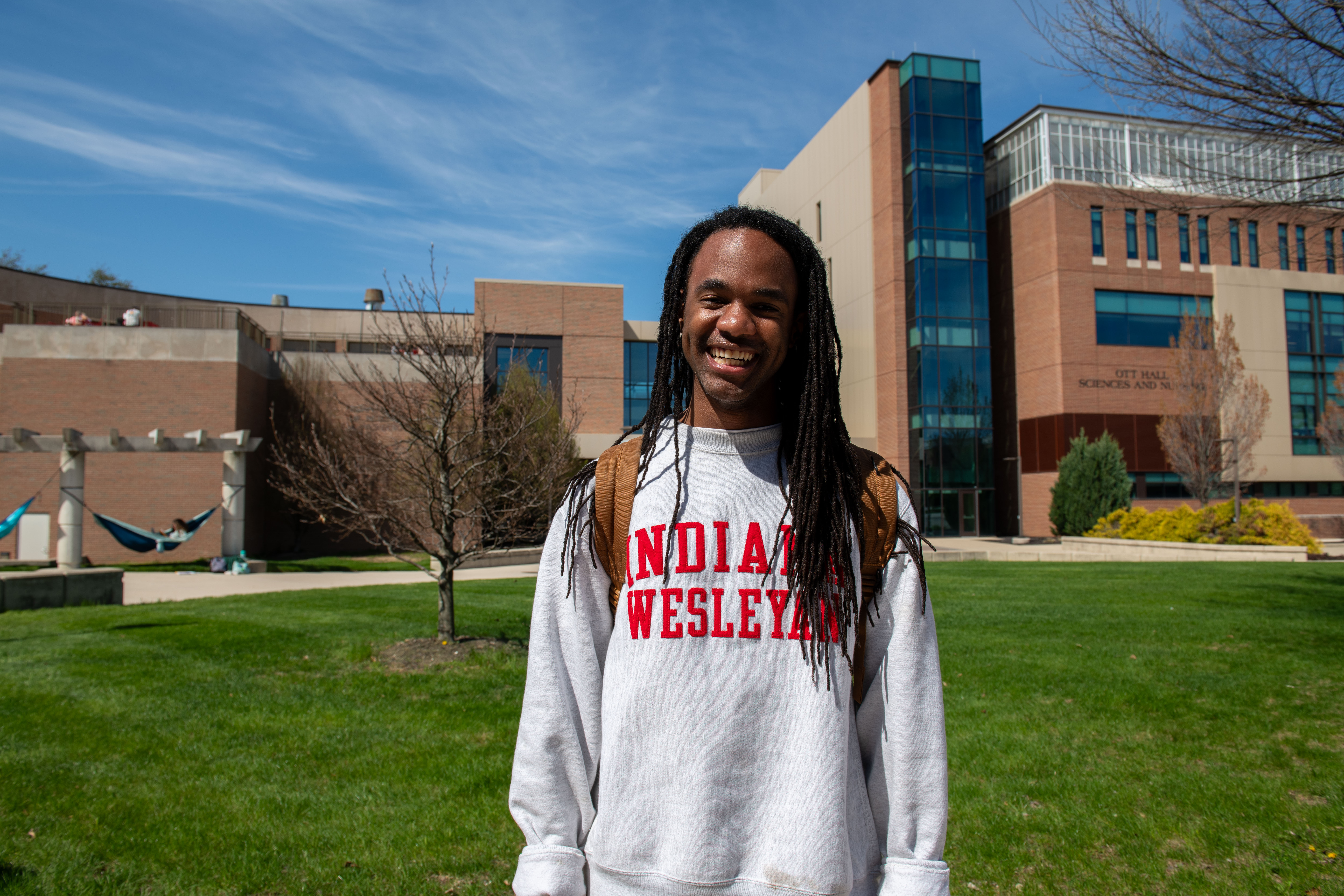 IWU student standing in front of Ott Hall and smiling at camera
