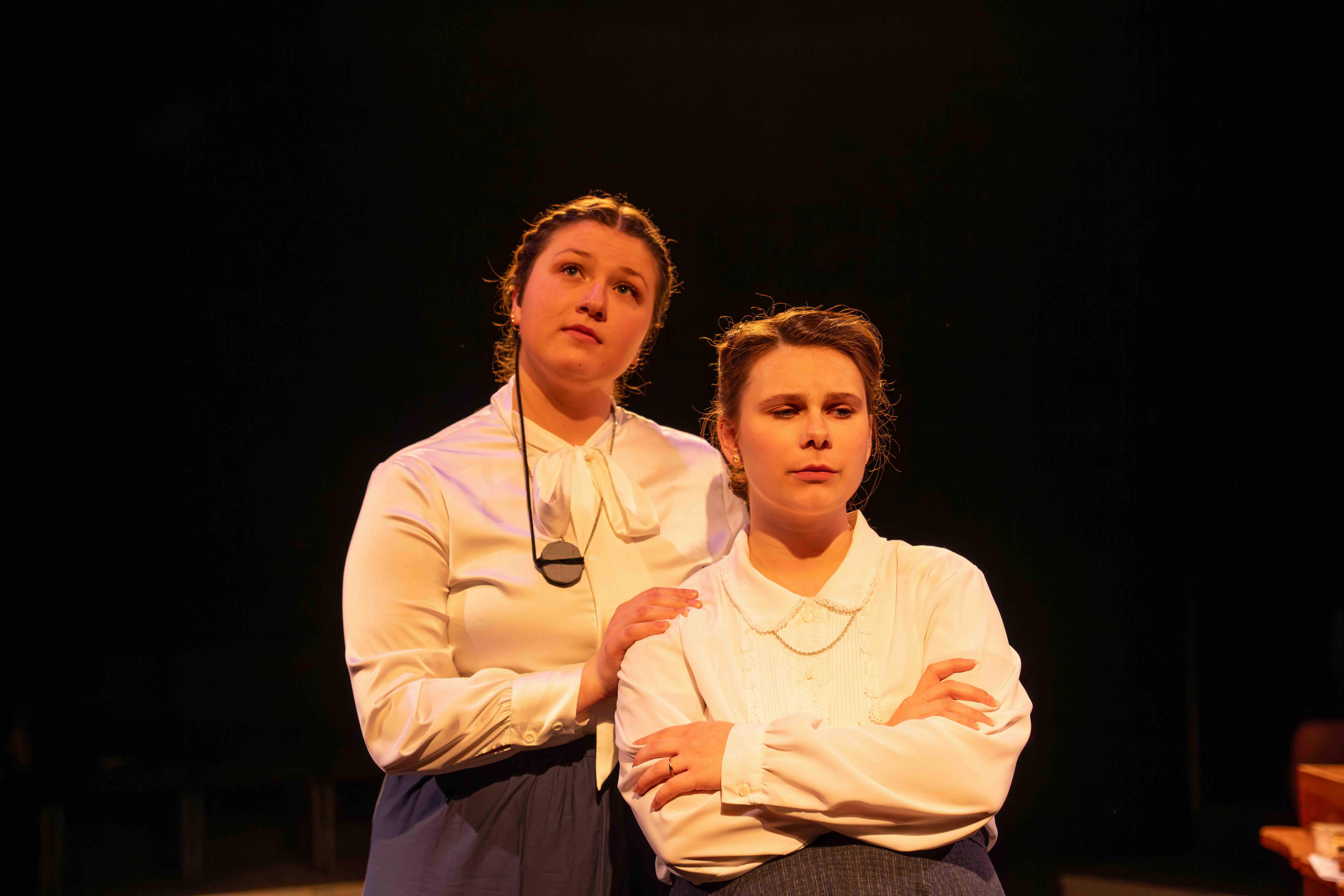 2 female characters in silent sky production, one slightly behind the other with hand on her shoulder while looking up.