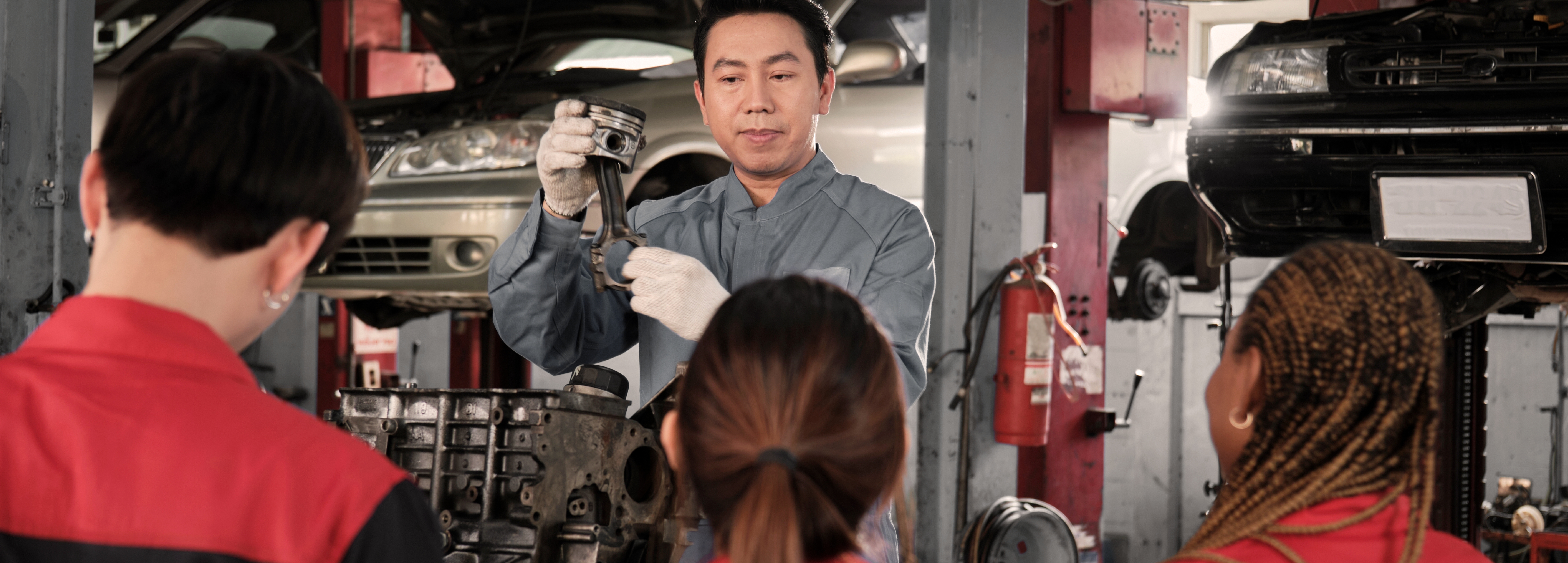 mechanic demonstrating a task with 3 students watching