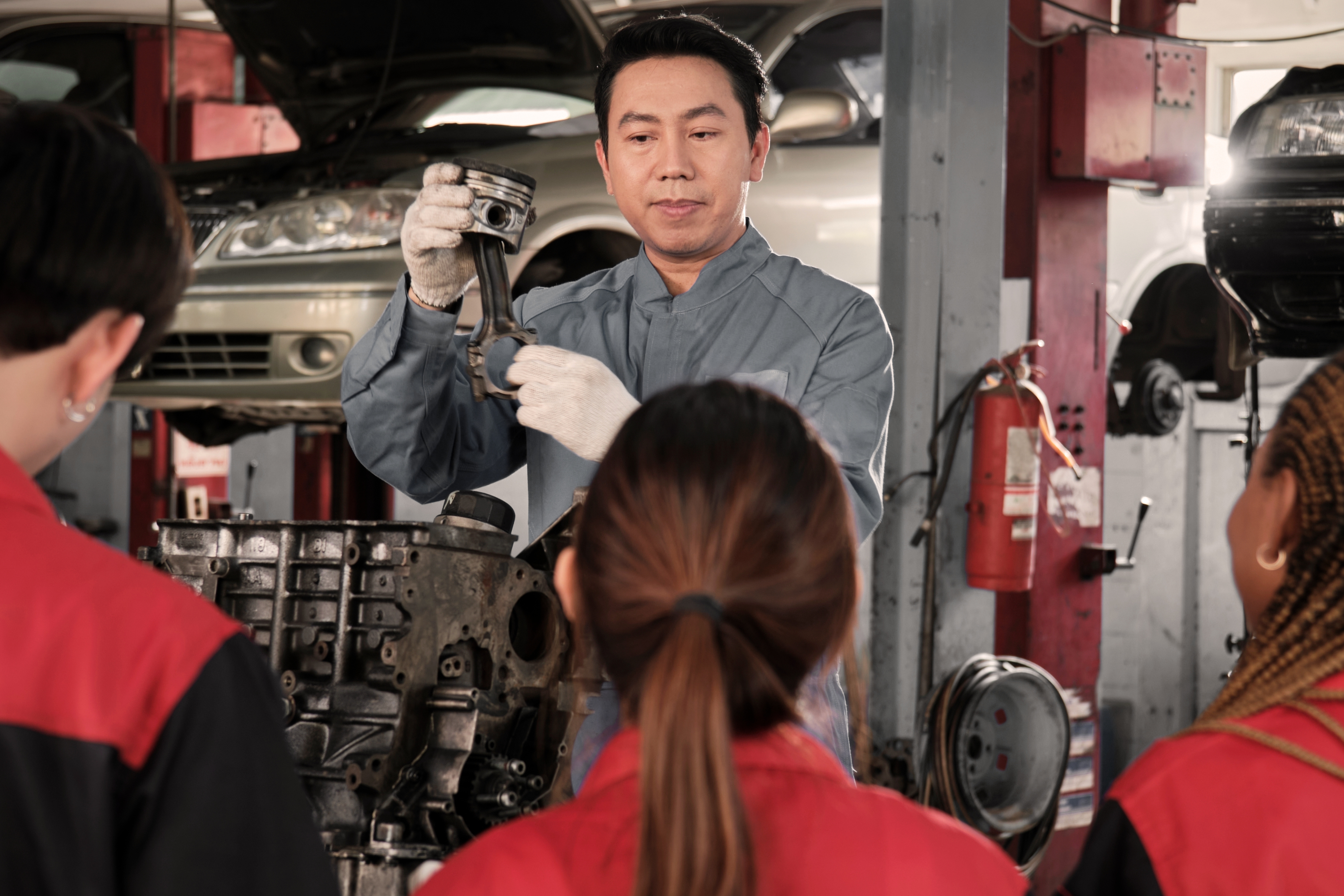mechanic demonstrating a task with 3 students watching
