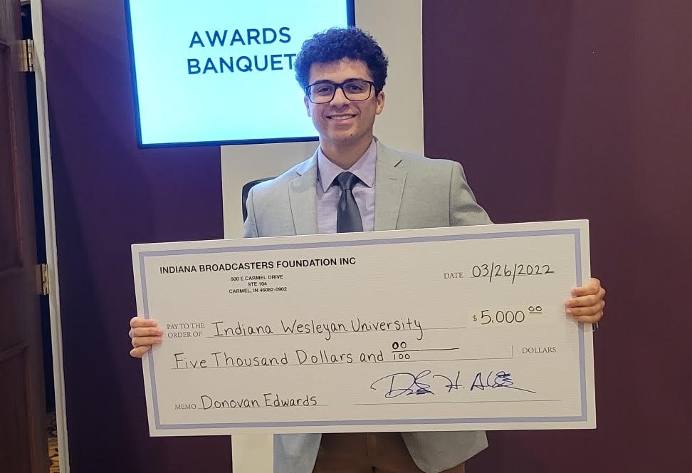 Donovan Edward holds his large scholarship check from the Indiana Broadcasters Association