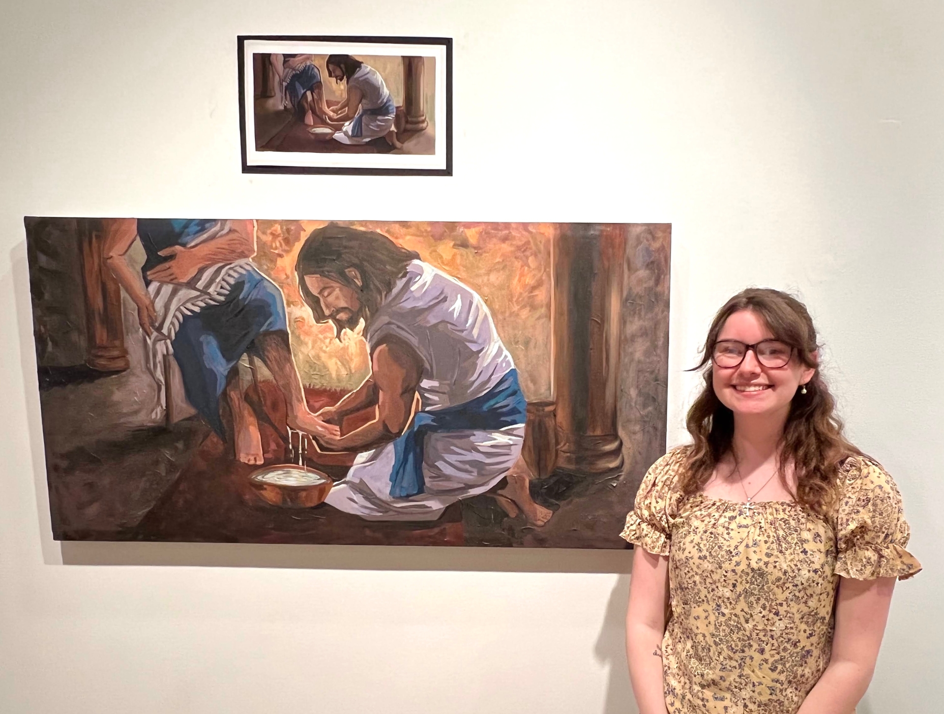 Morgan Coppel stands next to her painting of Jesus washing the feet of his disciples.