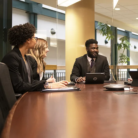 A group of people in professional suits sit around a conference table.