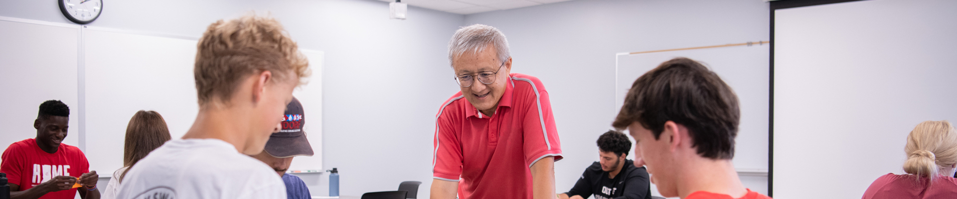 professor working with a group of students in the classroom