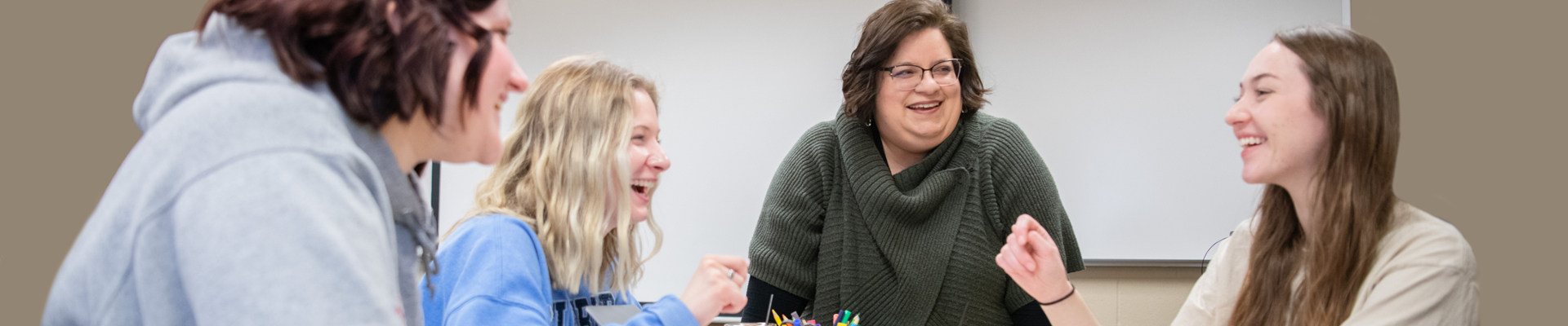 professor laughing with group of students in classroom