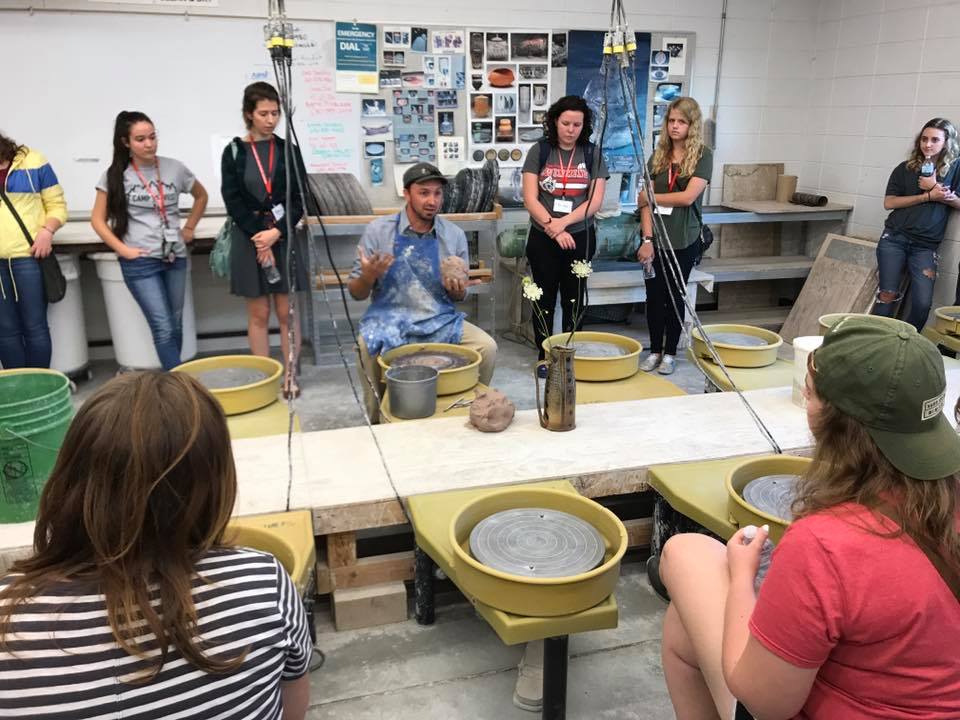 Students gather around professor in ceramics class
