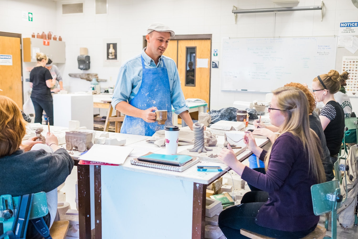 Professor helps students in ceramics class