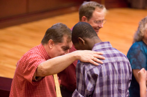Professor laying hand on a student and praying for him