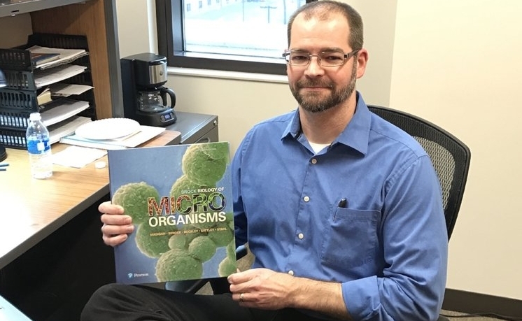 Dr. Matthew Sattley holding authored textbook