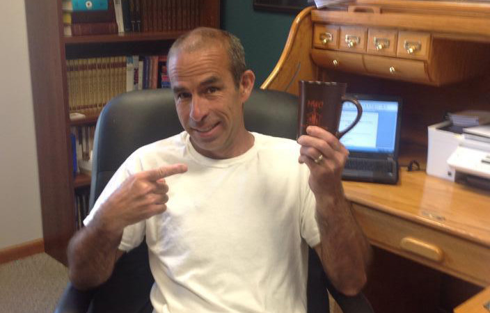 Brad Harris sitting in his office holding a coffee mug